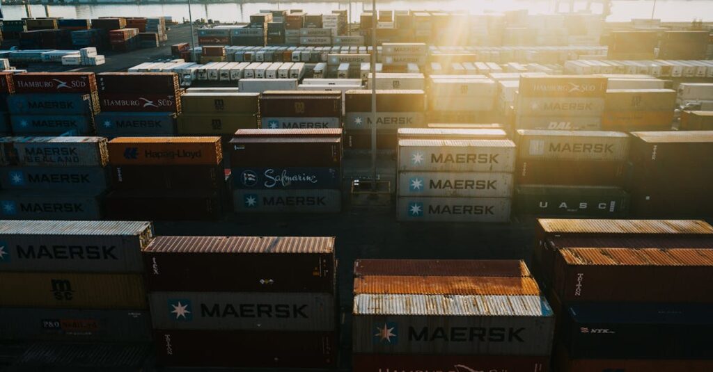 From above of different colored cargo containers placed in rows in industrial district in back lit